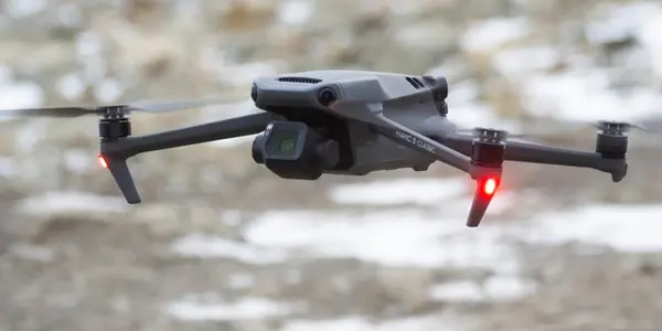 A black drone soaring in the sky, showcasing its sleek design against a clear blue background